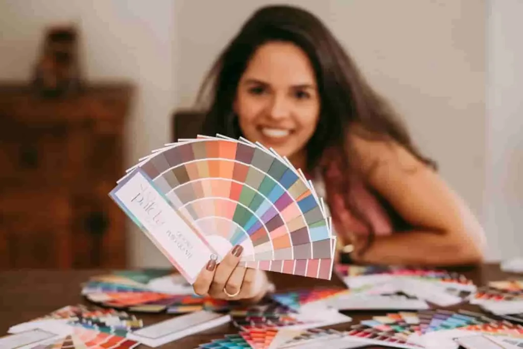 Personne souriante tenant des nuanciers : image illustrant le plaisir de créer une couleur palette personnalisée.