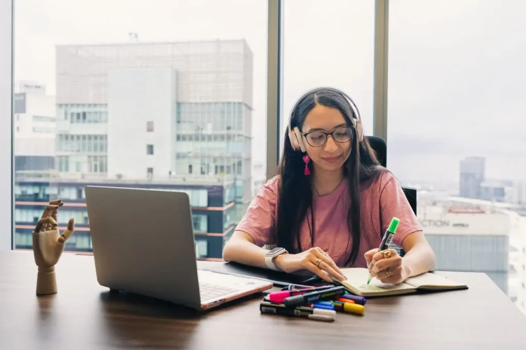 Personne en chemise rose et lunettes, concentrée sur son carnet, image d’un créateur seul développant son SaaS.