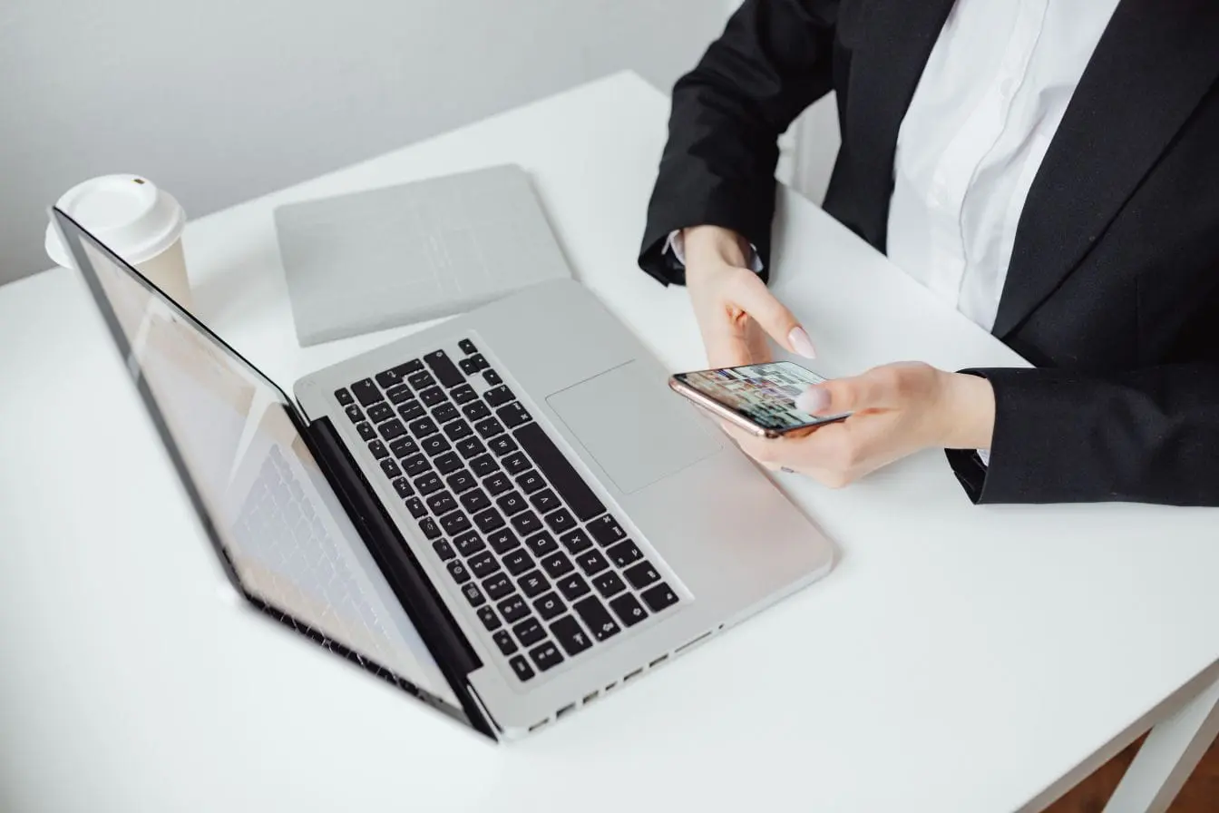 création d’un SaaS Entrepreneur seul à son bureau, ordinateur portable ouvert et smartphone en main, image qui illustre la création d’un SaaS en autonomie.