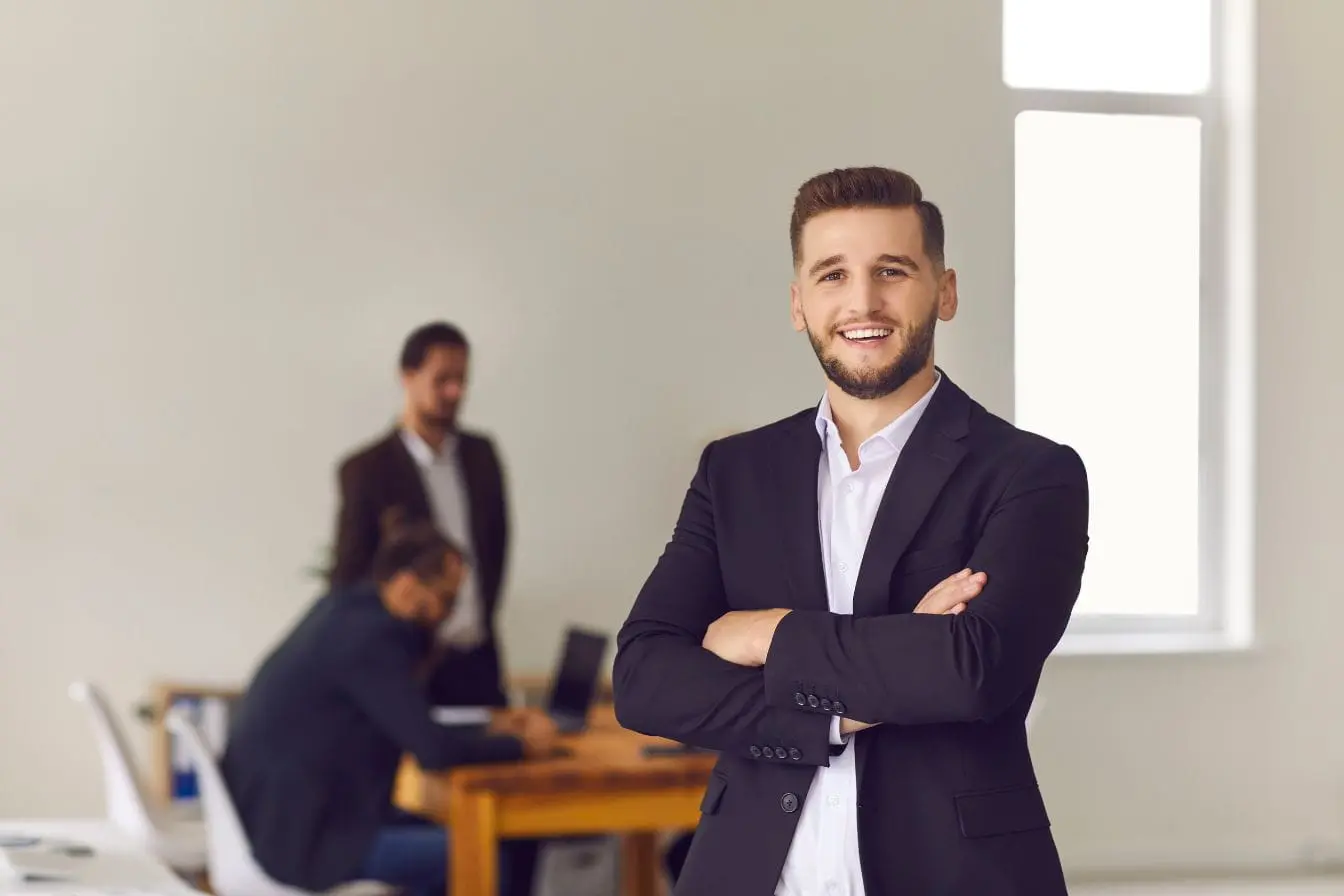 Professionnel en costume croisé devant fenêtre, image illustrant la réflexion stratégique nécessaire pour créer une franchise