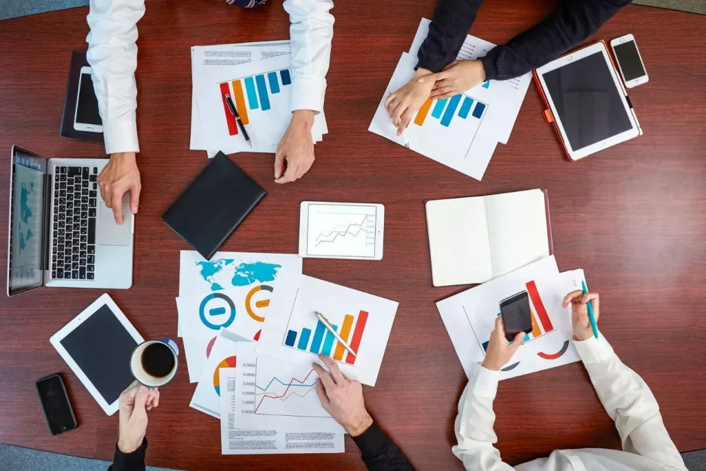 Réunion autour d’une grande table avec graphiques colorés, image qui illustre le framework AARRR et ses étapes clés du parcours client.