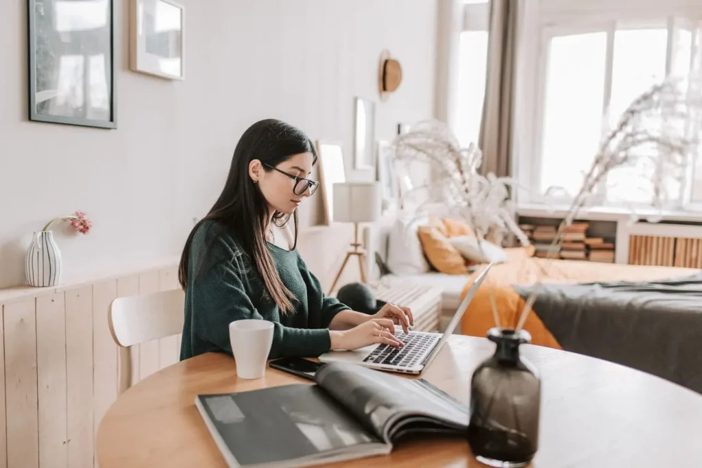 Personne assise à un bureau cosy travaillant sur laptop, image qui illustre le calcul de son TJM en freelance et la gestion de ses revenus.