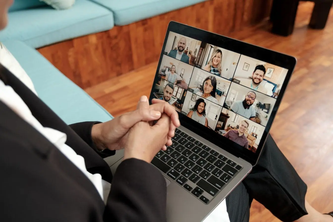 Personne assise devant ordinateur portable en visioconférence, image qui illustre la création d’une communauté en ligne active et connectée.
