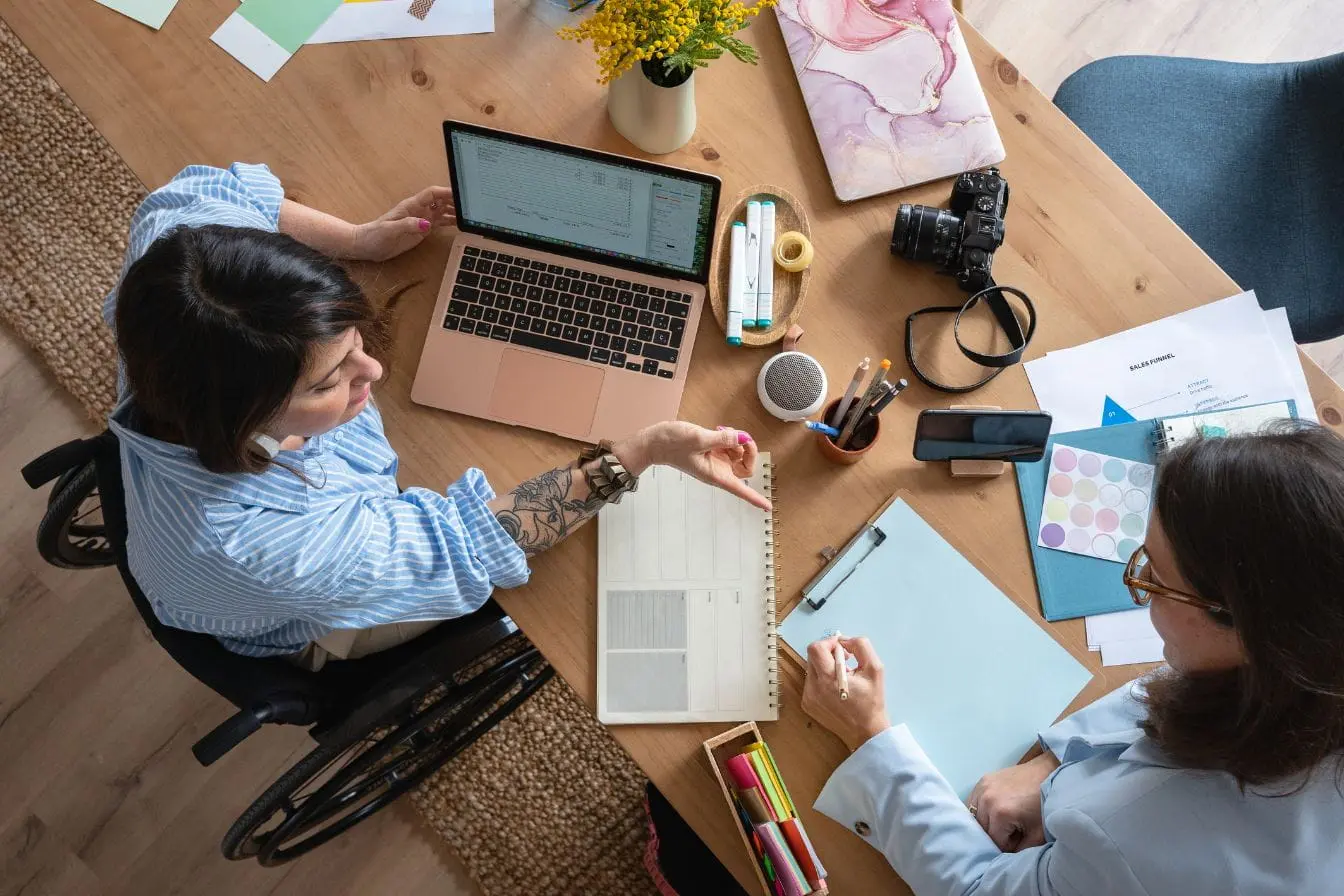 créer une marque blanche Deux personnes travaillent autour d’une table avec ordinateur et documents, image qui illustre la collaboration nécessaire pour créer une marque blanche.