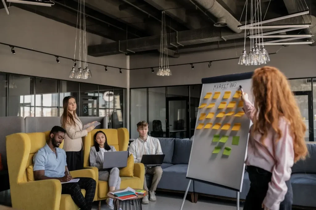 Groupe de personnes réunies autour d’un tableau couvert de post-it colorés, image qui illustre la créativité et la diversité d’un marketing inclusif.