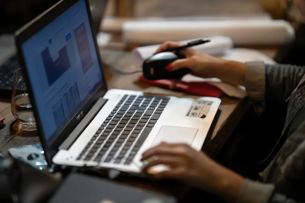 Personne travaillant sur ordinateur portable ASUS, image qui illustre l’importance du SLA pour garantir disponibilité et performance des services informatiques.