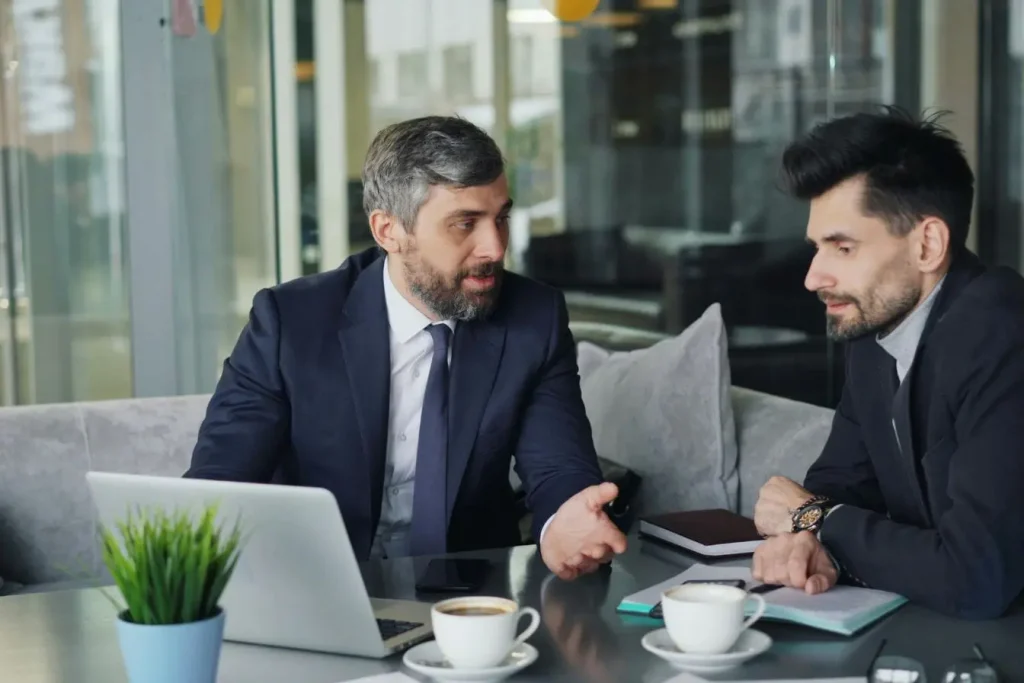 Bureau moderne avec café et smartphone posé, illustration du mentor qui conseille face au coach qui accompagne.