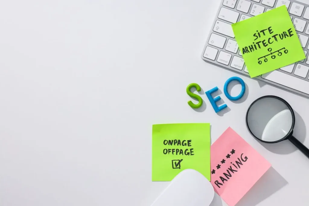 Bureau blanc avec clavier, loupe et post‑it SEO, reflet d’une optimisation Core Web Vitals pour améliorer architecture et performance.