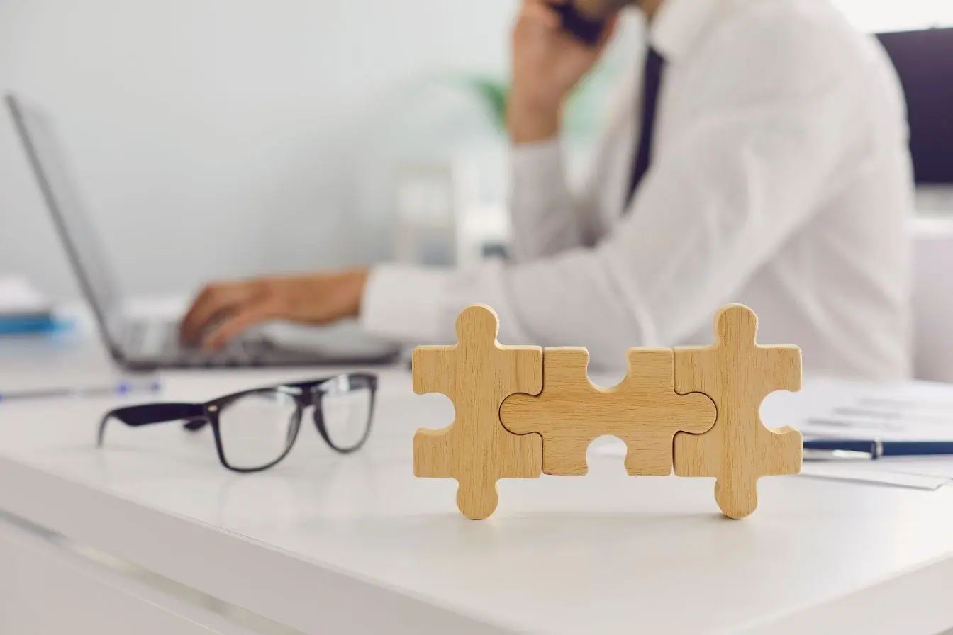 Bureau avec lunettes, stylo et puzzle en bois, reflet des stratégies de link juice et netlinking en SEO.