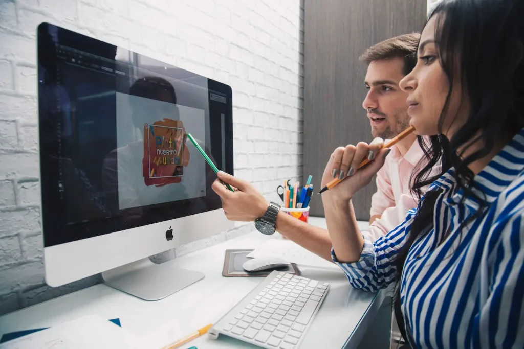 Deux personnes discutent devant écran affichant visuel coloré, image qui illustre le brand content face à la publicité classique.