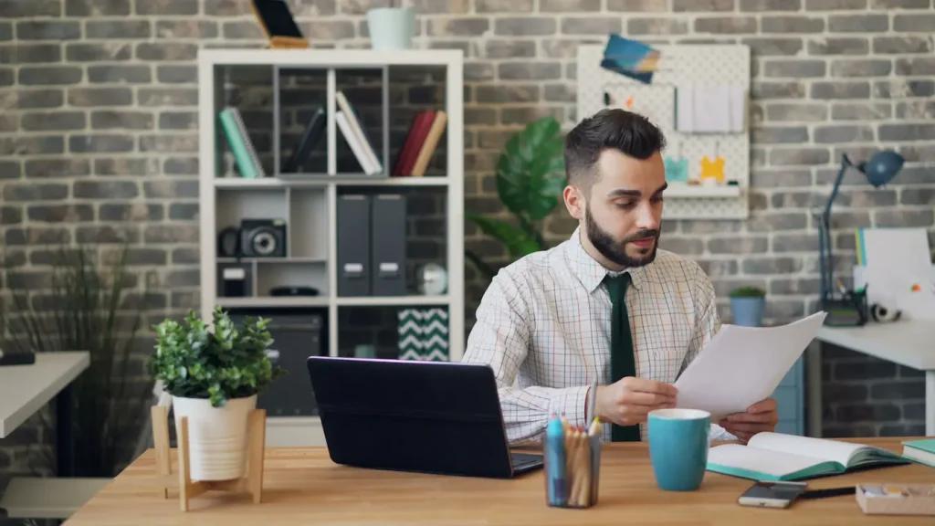 Personne assise à bureau moderne avec ordinateur et papiers, image qui illustre Business Angel vs Capital‑risqueur et leurs différences.
