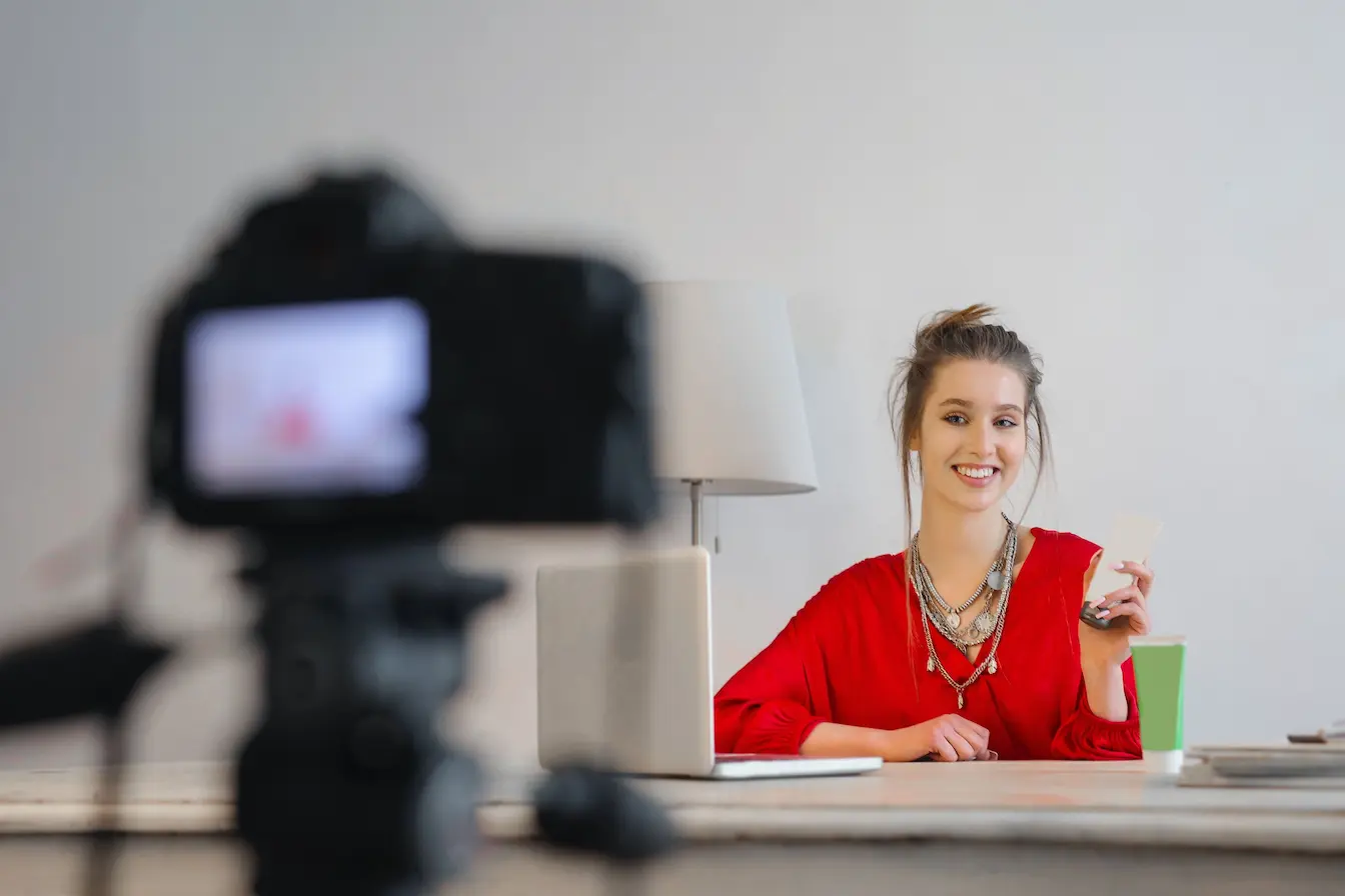 Créatrice de contenu filmée devant caméra avec laptop, image qui illustre le brand content face à la publicité classique.