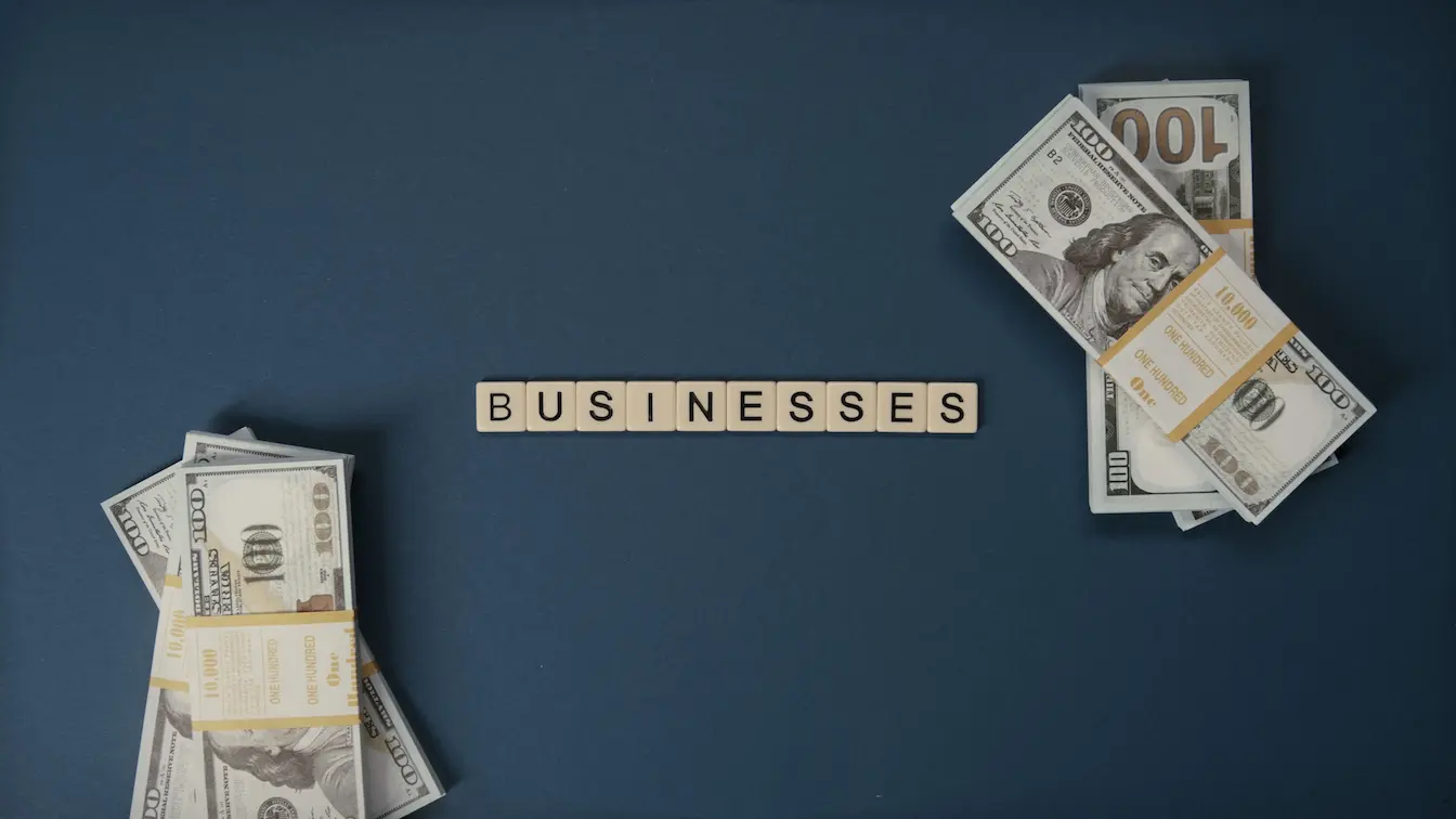 billets de cent dollars Deux piles de billets de cent dollars encadrant mot businesses, image symbolisant le capital social minimum d’une SASU et les apports nécessaires.