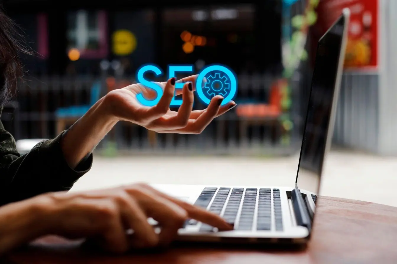 hologramme SEO Personne utilisant laptop avec hologramme SEO bleu, reflet d’une stratégie de maillage interne pour optimiser liens et visibilité.