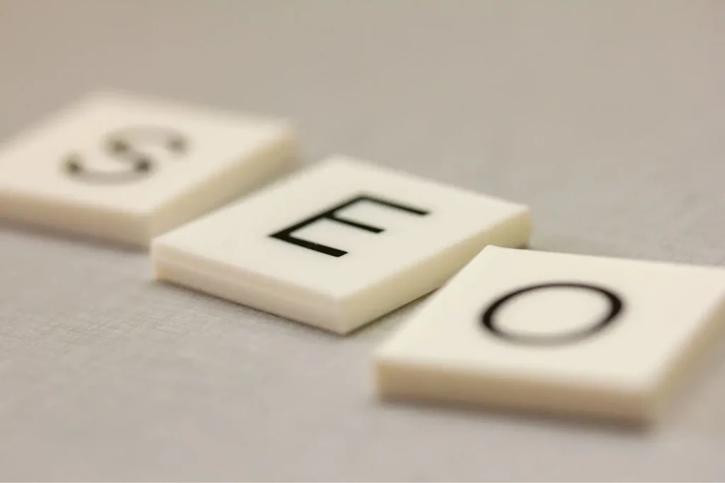Trois tuiles blanches alignées formant les lettres SEO, reflet des stratégies SEO YouTube pour optimiser visibilité et audience des vidéos.