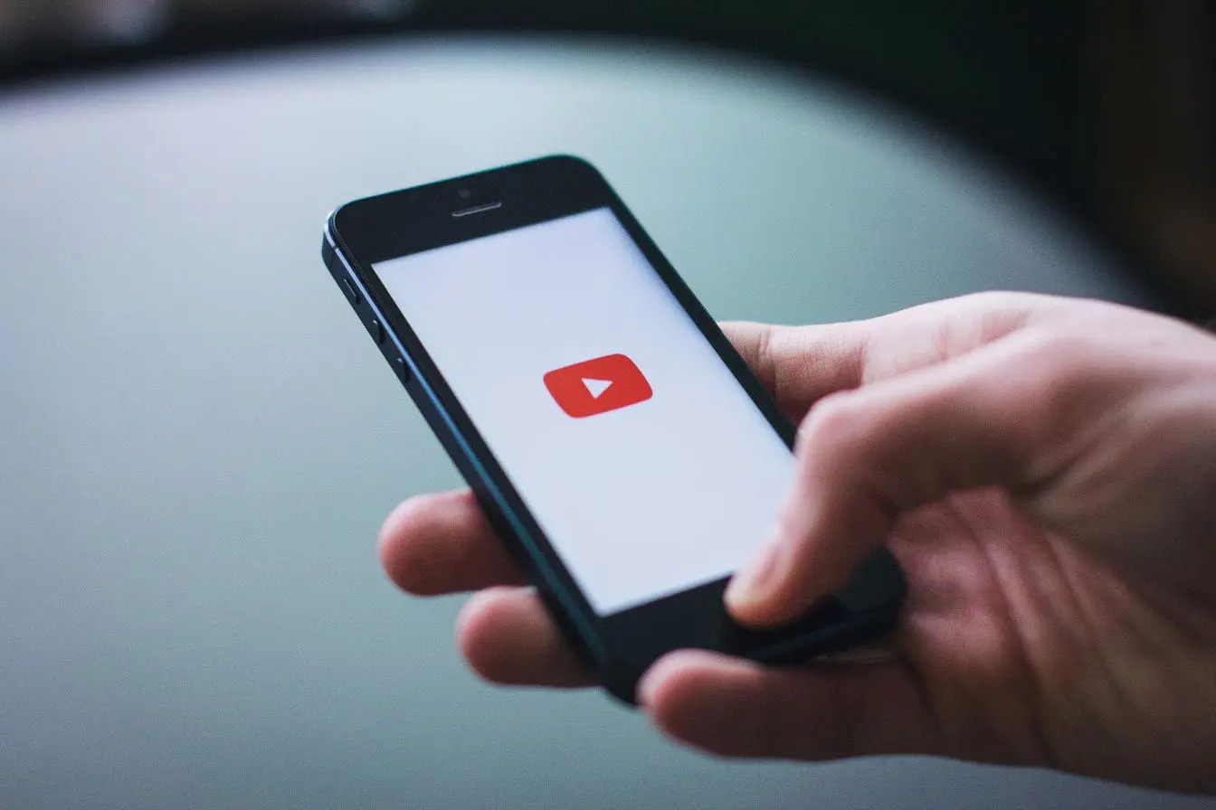 logo YouTube Main tenant smartphone affichant logo YouTube, reflet des stratégies SEO pour optimiser visibilité des vidéos.