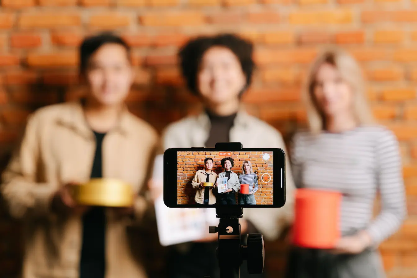 marketing d’influence Smartphone filmant trois personnes avec objets colorés, image d’un marketing d’influence et micro‑influenceurs en pleine création de contenu.