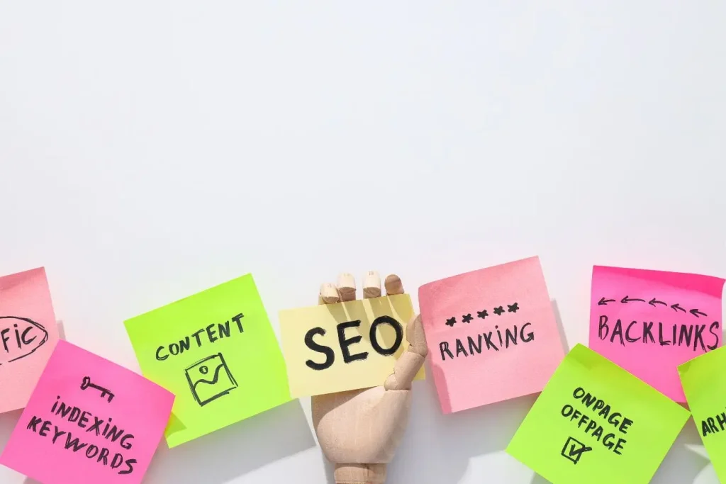 Main articulée tenant post‑it SEO entouré de notes colorées, reflet des piliers du voice search et référencement.