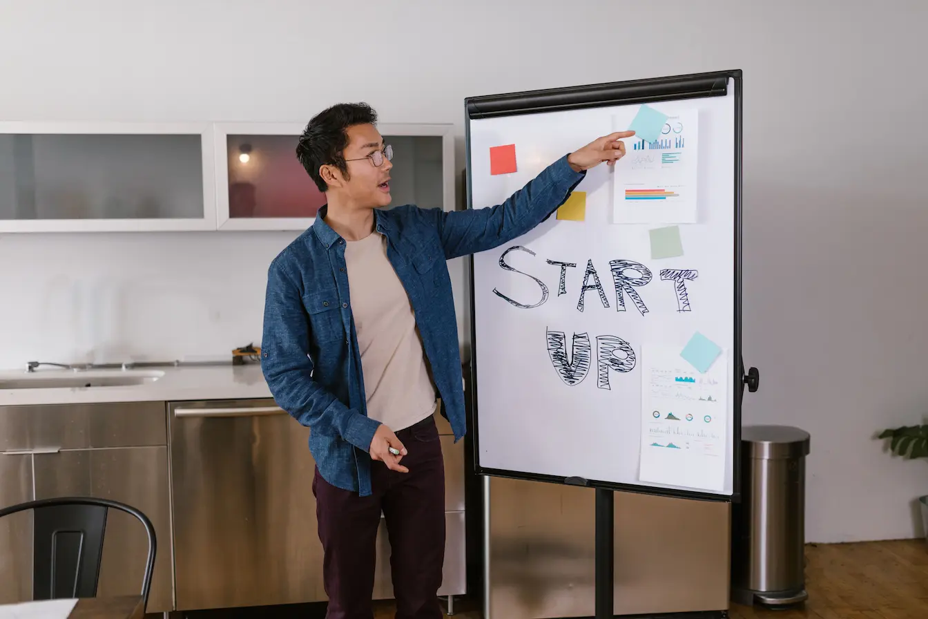 Personne en bureau moderne présentant tableau avec mot START UP, reflet du comparatif Incubateur vs Accélérateur de startup.