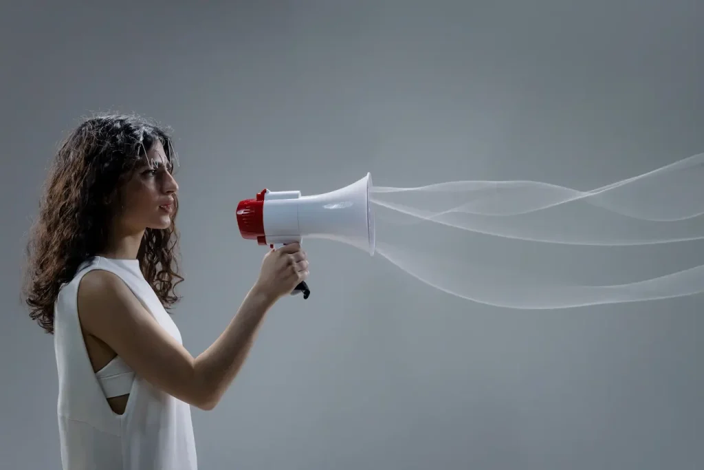 Personne tenant un mégaphone blanc et rouge, image qui illustre le storytelling de marque et la puissance de la voix pour transmettre un message.