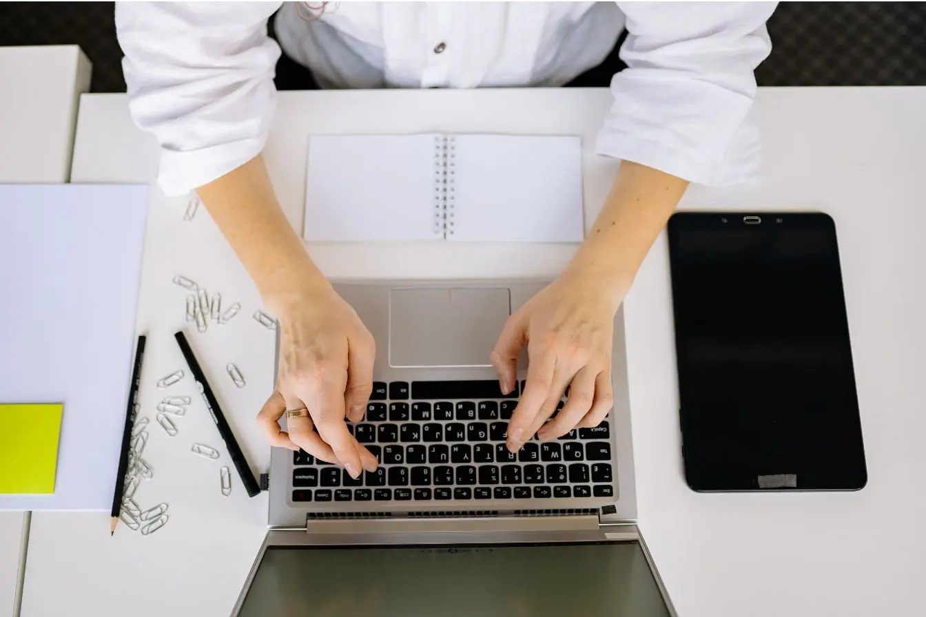 Copywriting Une personne tapant sur un ordinateur portable pour rédiger des textes de vente avec le copywriting et techniques de persuasion sur un bureau blanc bien organisé.
