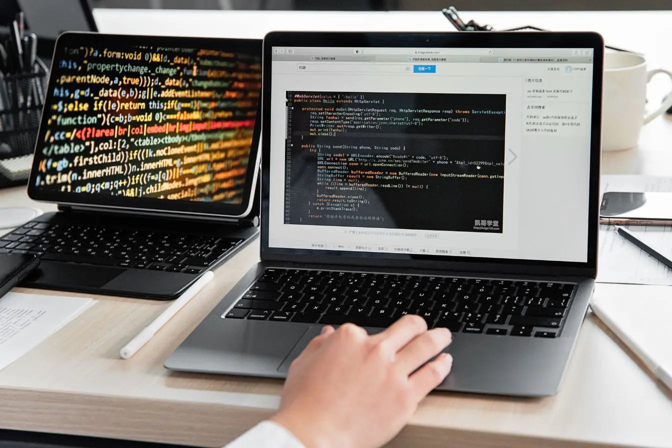 dette technique en informatique Développeur travaillant sur plusieurs écrans affichant du code source, illustrant la dette technique accumulée au fil des choix de développement d’un projet
