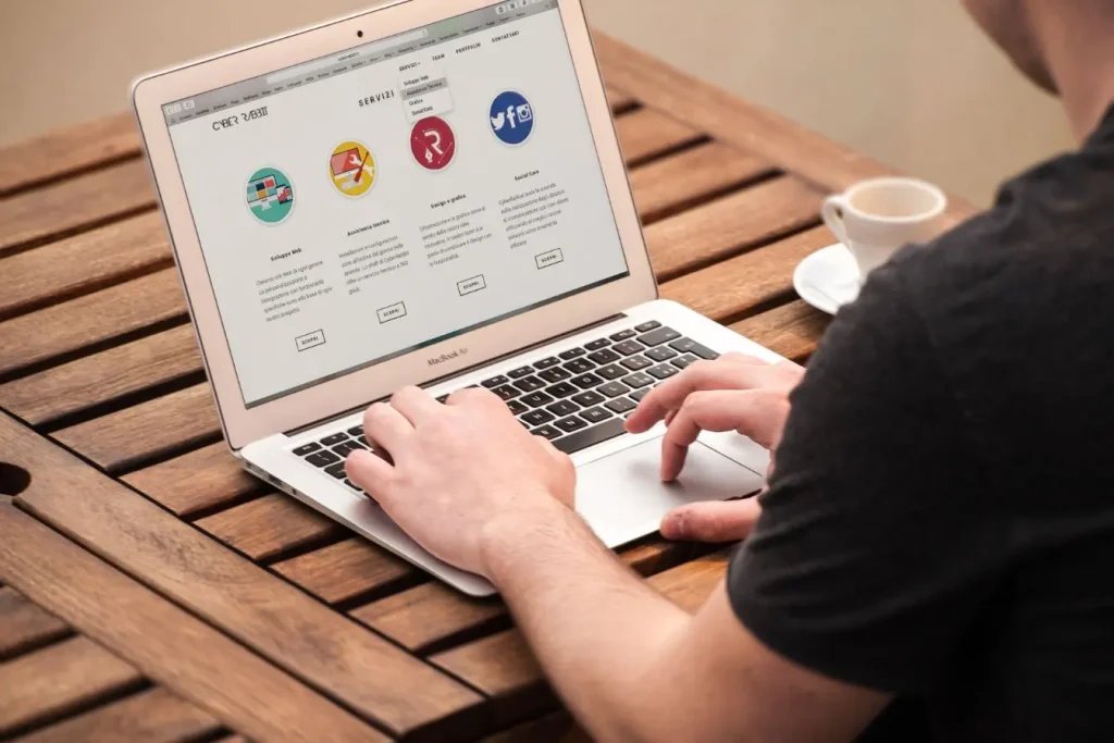 Personne utilisant MacBook Air affichant site de services numériques, symbole des solutions modulaires offertes par un Headless CMS.