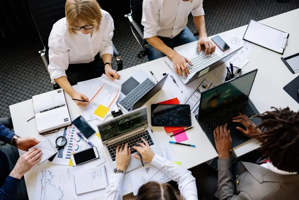 Une équipe de professionnels travaillant ensemble autour d'une grande table, idéale pour illustrer une stratégie de prospection LinkedIn collaborative.