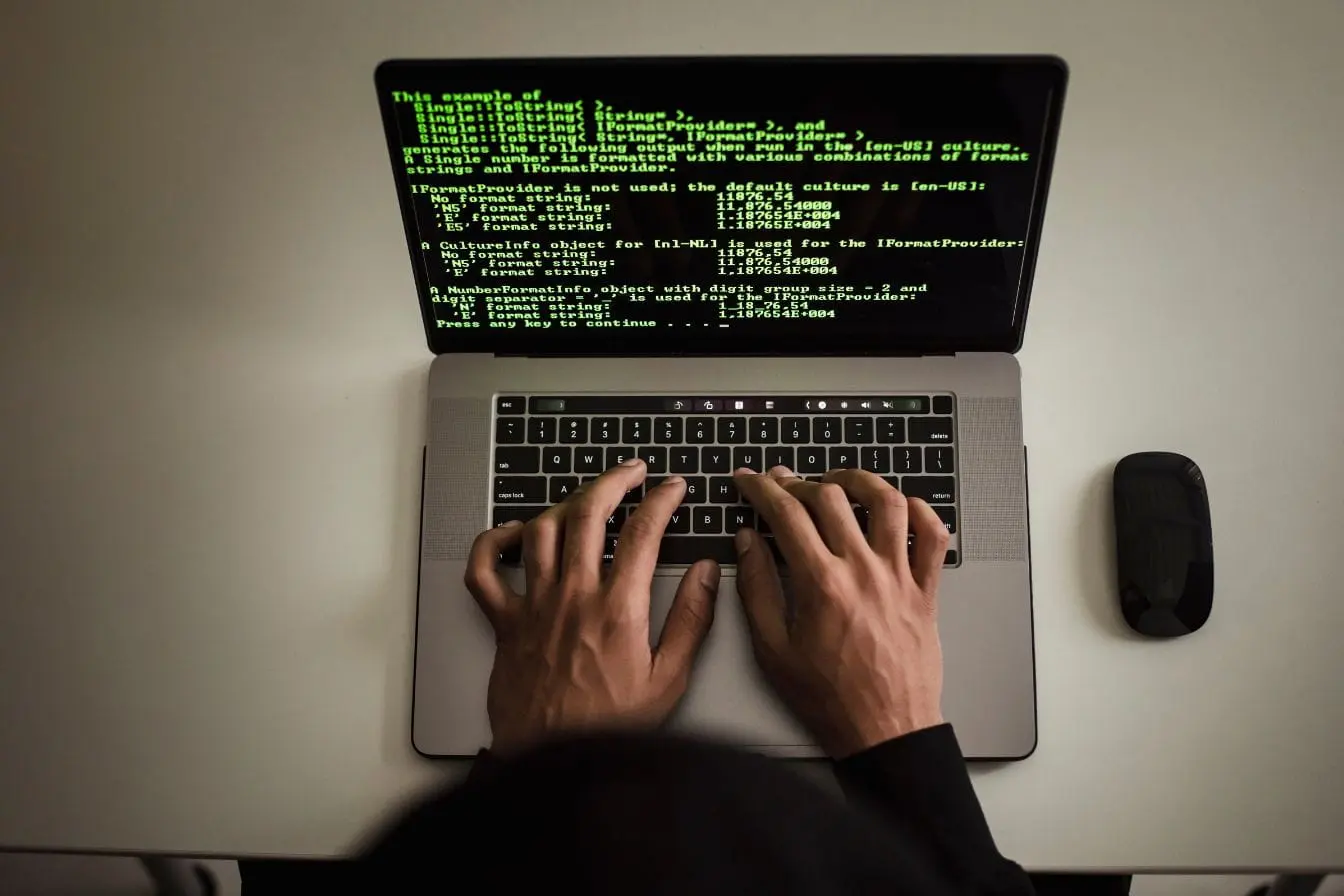ransomware en entreprise Personne tapant sur clavier d’ordinateur portable affichant code vert, symbole des menaces de ransomware en entreprise.